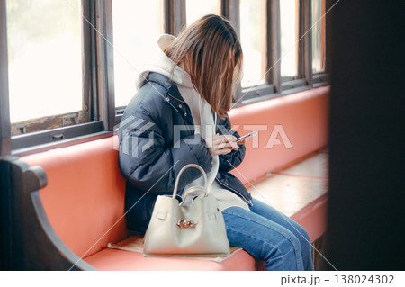 電車内でスマホを操作する20代女性のポートレート 138024302
