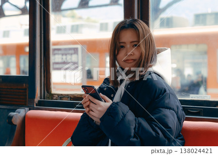 電車内でスマホを操作する20代女性のポートレート 138024421