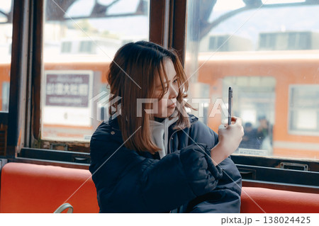 電車内でスマホを操作する20代女性のポートレート 138024425