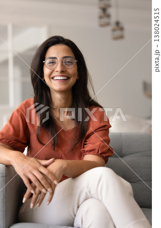 Confident woman seated in armchair smiling at camera Confident woman seated in armchair smiling at camera 138024515
