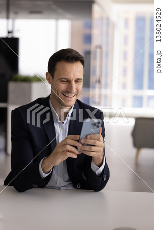 Smiling Hispanic office employee checking smartphone at workplace desk 138024529