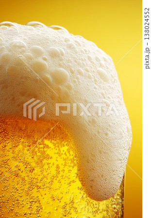 Fizzy beer glass with foam in closeup on warm golden background, concept of refreshment and celebration 138024552