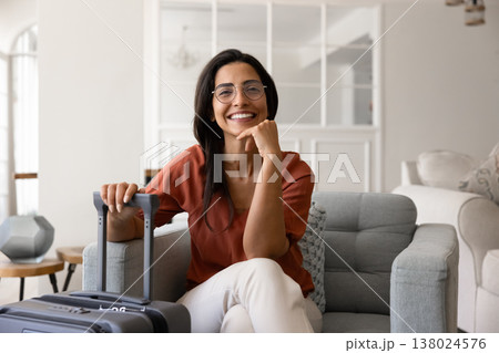 Portrait of Brazilian tourist woman sitting in armchair with suitcase 138024576