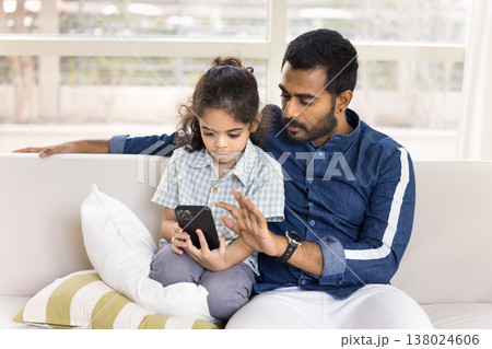 Young dad and little son using smartphone seated on sofa Young dad and little son using smartphone seated on sofa 138024606