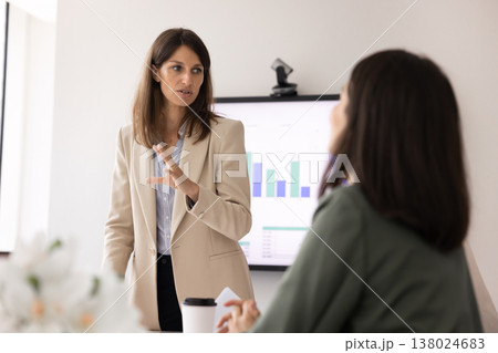 Confident businesswoman standing and speaking during meeting in modern office 138024683