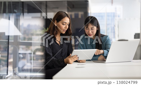 Serious diverse female managers analyzing online content on tablet 138024799