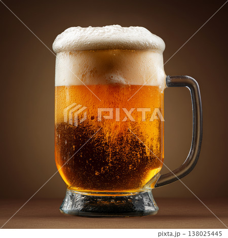 Glass of craft amber beer with foam on brown wooden table and solid backdrop, concept of refreshment and taste feel 138025445