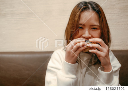 おにぎりを食べる笑顔の20代女性 138025501