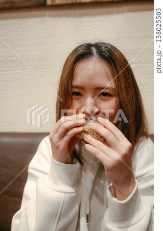 おにぎりを食べる笑顔の20代女性 138025503