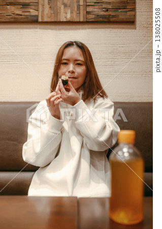 おにぎりを食べる笑顔の20代女性 138025508