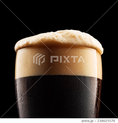 Foamy dark stout beer in a pint glass with creamy foam head, isolated on black background, concept of refreshment and taste 138025570