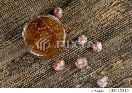 orange jam made from oranges and fresh citrus fruits, orange jam with dried kumquat fruits in sweet syrup, jam for making desserts in a round glass jar on a wooden table 138025810