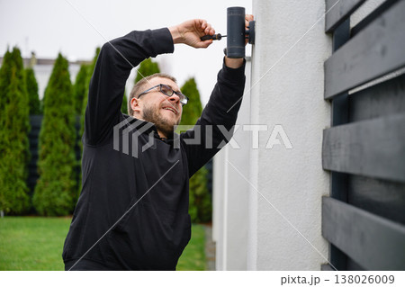 Man installing outdoor wall light with screwdriver Man installing outdoor wall light with screwdriver 138026009