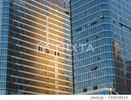 Gold and blue glass skyscrapers stand tall as window washers clean their modern exteriors 138028924