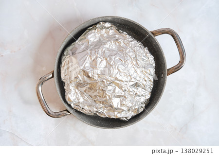 Cooking pork shoulder in a pot covered with foil for slow roasting Cooking pork shoulder in a pot covered with foil for slow roasting 138029251