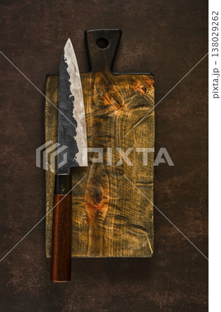 Knife on wooden cutting board placed on dark surface for food preparation 138029262