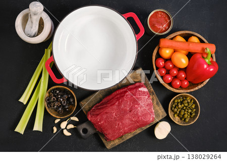 Preparing ingredients for a beef stew in a kitchen setting with fresh vegetables and meat 138029264