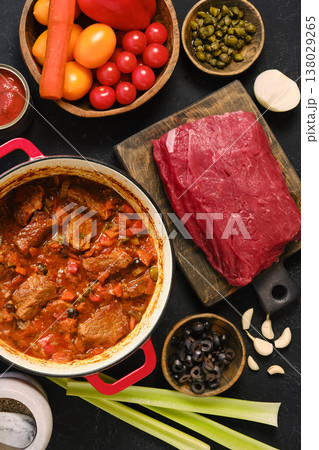 Beef stew preparation with fresh ingredients and chunks of meat on a wooden cutting board Beef stew preparation with fresh ingredients and chunks of meat on a wooden cutting board 138029265