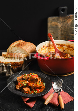 Warm beef stew served with bread on a table with rustic decor in a cozy kitchen setting Warm beef stew served with bread on a table with rustic decor in a cozy kitchen setting 138029269