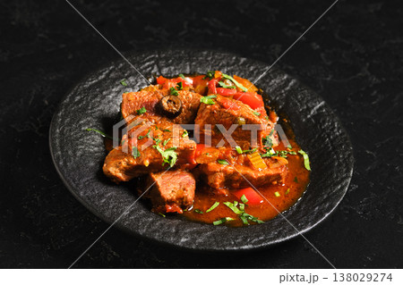Warm beef stew served with vegetables on a black plate in a cozy kitchen setting Warm beef stew served with vegetables on a black plate in a cozy kitchen setting 138029274