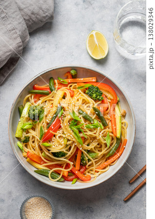 Stir fry wok noodles with vegetables in a plate on a light background with chopsticks 138029346
