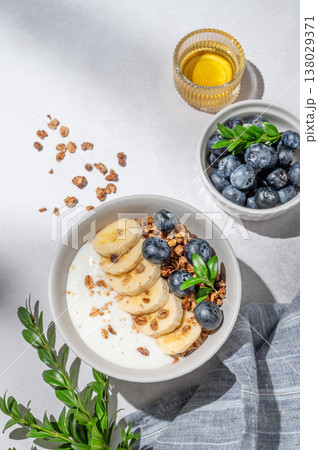 Natural greek yogurt with granola, blueberry and banana in a bowl on a light concrete background Natural greek yogurt with granola, blueberry and banana in a bowl on a light concrete background 138029371