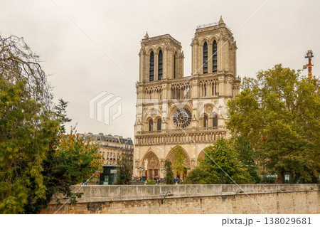 Notre Dame Cathedral in Paris, France, from the Seine riverbank, seeing its iconic gothic architecture under a cloudy sky 138029681