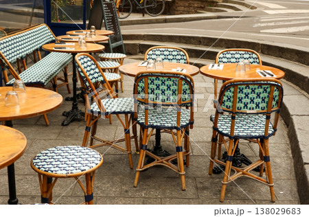 Empty outdoor cafe terrace in Paris, France, with classic bistro rattan chairs and wooden tables offering a Parisian lifestyle scene 138029683