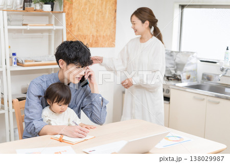 ダイニングで子どもの世話をしながら電話で仕事する若い父親 在宅ワークの育児風景 138029987