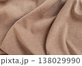 High-quality close-up of soft brown velour or faux suede fabric. The matte surface features gentle, flowing draping folds and soft shadows, creating a luxurious and tactile texture. 138029990