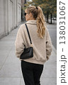 ベージュのボアジャケットとサングラスを着けて街を歩く若い女性のモダンな都会ファッションライフスタイル 138031067