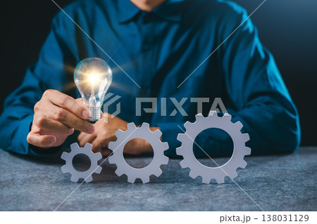 Business manager holds light ideas concept project gear management, devops process automation deploy, hand holds bright bulb near white gear wheels for optimization, efficiency Business manager holds light ideas concept project gear management, devops process automation deploy, hand holds bright bulb near white gear wheels for optimization, efficiency 138031129