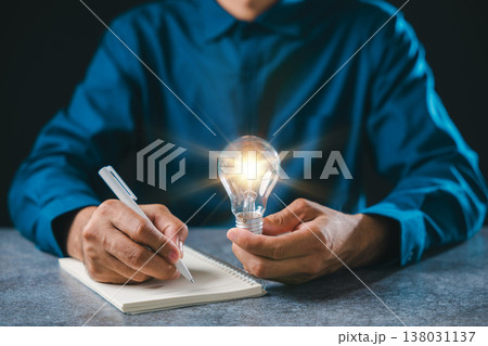 Creative mindset lightbulb idea business innovation insight concept, person writing notes in notebook using white pen on stone surface while glowing light bulb represents strategy Creative mindset lightbulb idea business innovation insight concept, person writing notes in notebook using white pen on stone surface while glowing light bulb represents strategy 138031137