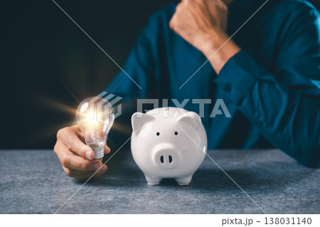 Innovation begins when hand holds glowing lightbulb by white piggy bank for financial growth, business innovation provides knowledge, research offers creative idea for saving money 138031140