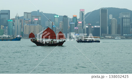 Traditional Chinese red sail junk boat sailing on Victoria Harbour with Hong Kong skyline background 138032425