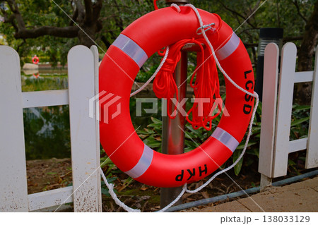 Red lifebuoy on fence near water in Hong Kong park safety equipment 138033129