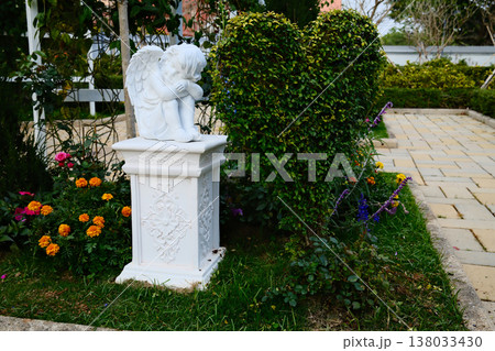 upid sculpture standing in outdoor garden surrounded with green heart shaped bush upid sculpture standing in outdoor garden surrounded with green heart shaped bush 138033430