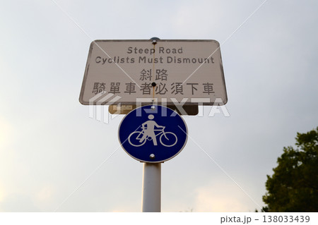 Steep road cyclists must dismount bilingual warning sign with bicycle symbol on pole in Hong Kong 138033439