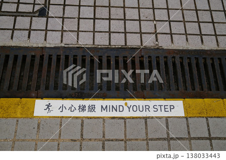 Mind Your Step bilingual Chinese English safety warning text on yellow line at Hong Kong station floor Mind Your Step bilingual Chinese English safety warning text on yellow line at Hong Kong station floor 138033443