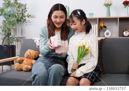 Mother and daughter exchanging gifts on a cozy couch 138033737