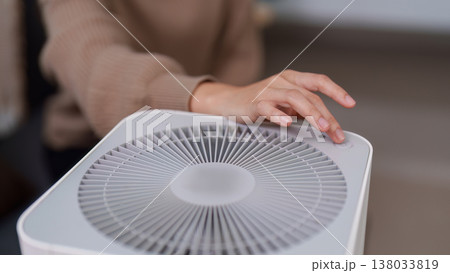 Hand adjusting settings on a modern air purifier Hand adjusting settings on a modern air purifier 138033819
