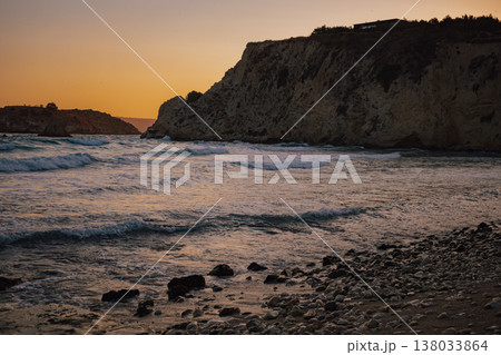 Golden orange sunset sky over ocean waves near steep coastal cliff and rocky island landscape view Golden orange sunset sky over ocean waves near steep coastal cliff and rocky island landscape view 138033864