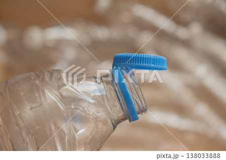 Water bottle cap is off and resting on top of an empty plastic bottle near crumpled plastic Water bottle cap is off and resting on top of an empty plastic bottle near crumpled plastic 138033888