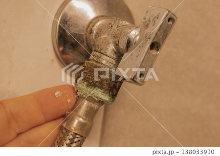 Female hand on an old, oxidized water faucet with hose: moisture damage and limescale Female hand on an old, oxidized water faucet with hose: moisture damage and limescale 138033910