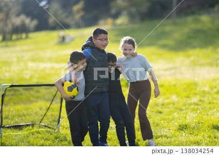 Diverse children playing soccer, embracing friendship in park Diverse children playing soccer, embracing friendship in park 138034254