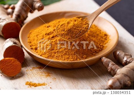 Turmeric powder and fresh turmeric roots on a wooden board. Organic healthy spice Turmeric powder and fresh turmeric roots on a wooden board. Organic healthy spice 138034351