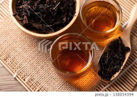 Hot black tea in a glass cup with dry tea leaves, Asian healthy beverage culture 138034394