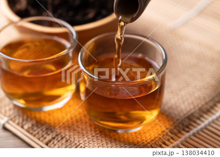 Pouring hot black tea from teapot into a glass cup, Asian healthy beverage culture 138034410