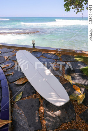 Surfboard on stone path by ocean 138034441
