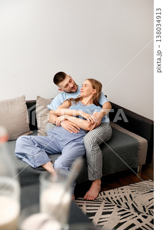 Couple shares a cozy moment on a sofa in their living room during the afternoon while enjoying each others company and conversation 138034913